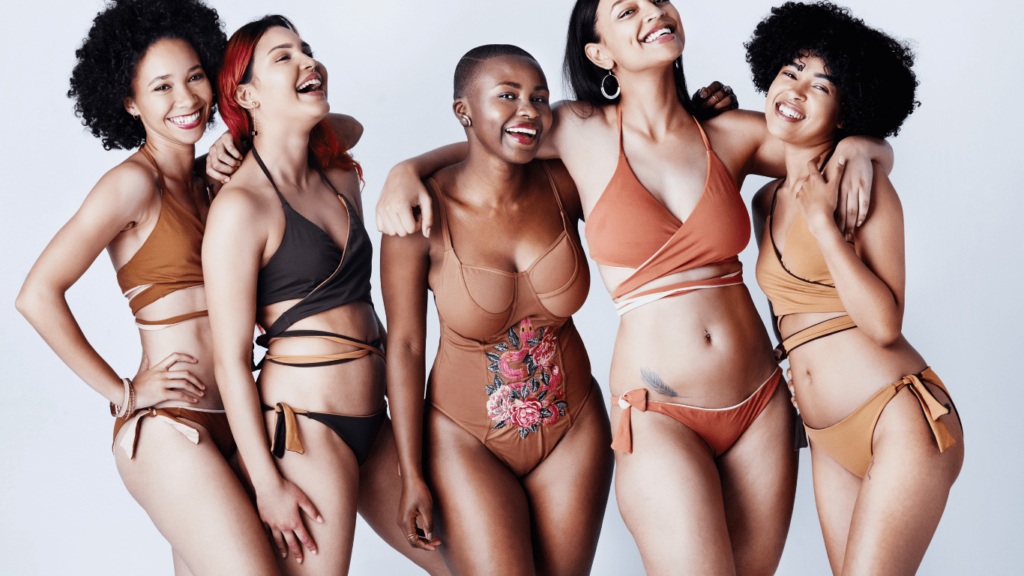 Studio shot of a group of beautiful young women in posing together in swimwear against a gray background