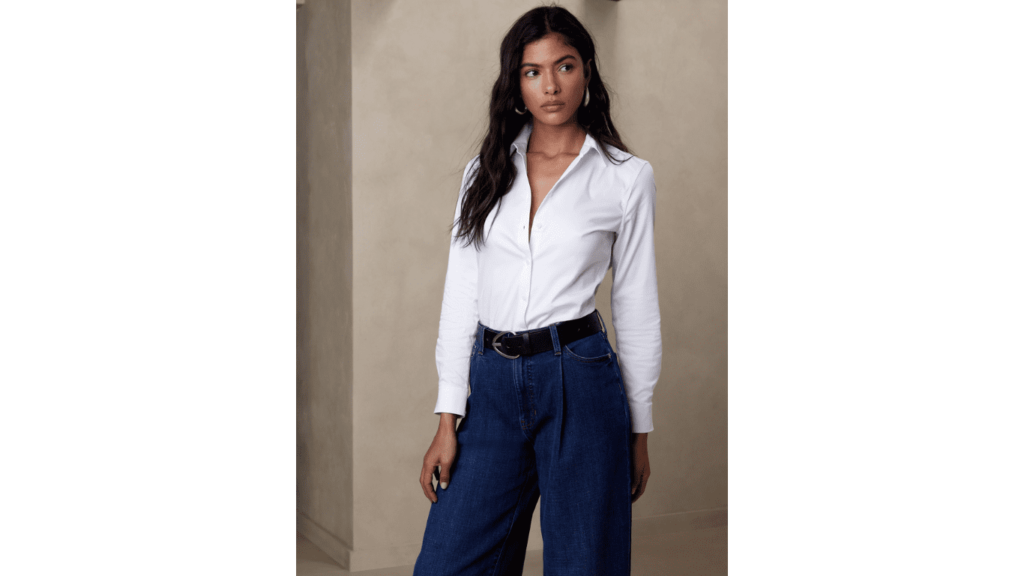 Stylish brown-skinned woman in a crisp white shirt paired with dark blue jeans and a black belt
