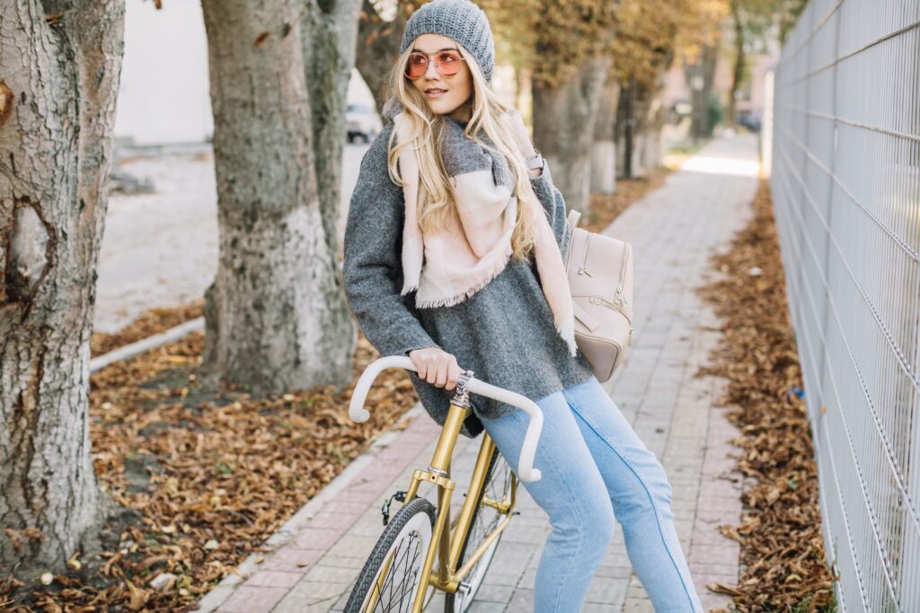 Captivating woman riding her bicycle gracefully, positioned near a fence.