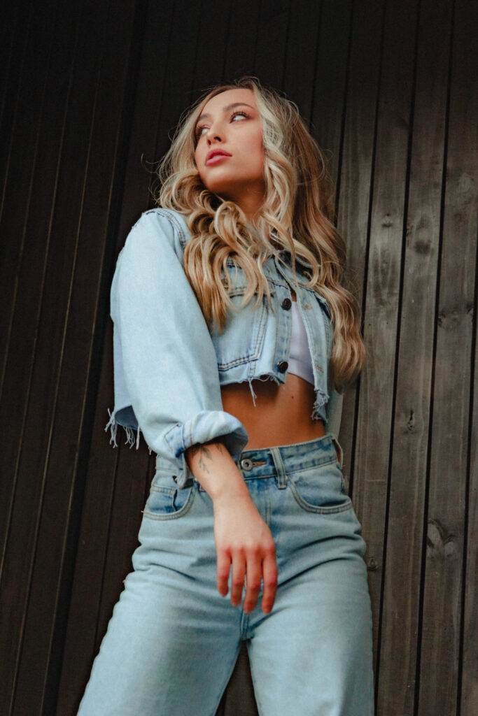Girl wearing a coordinated denim outfit featuring a cropped jacket with stylishly rolled-up sleeves.