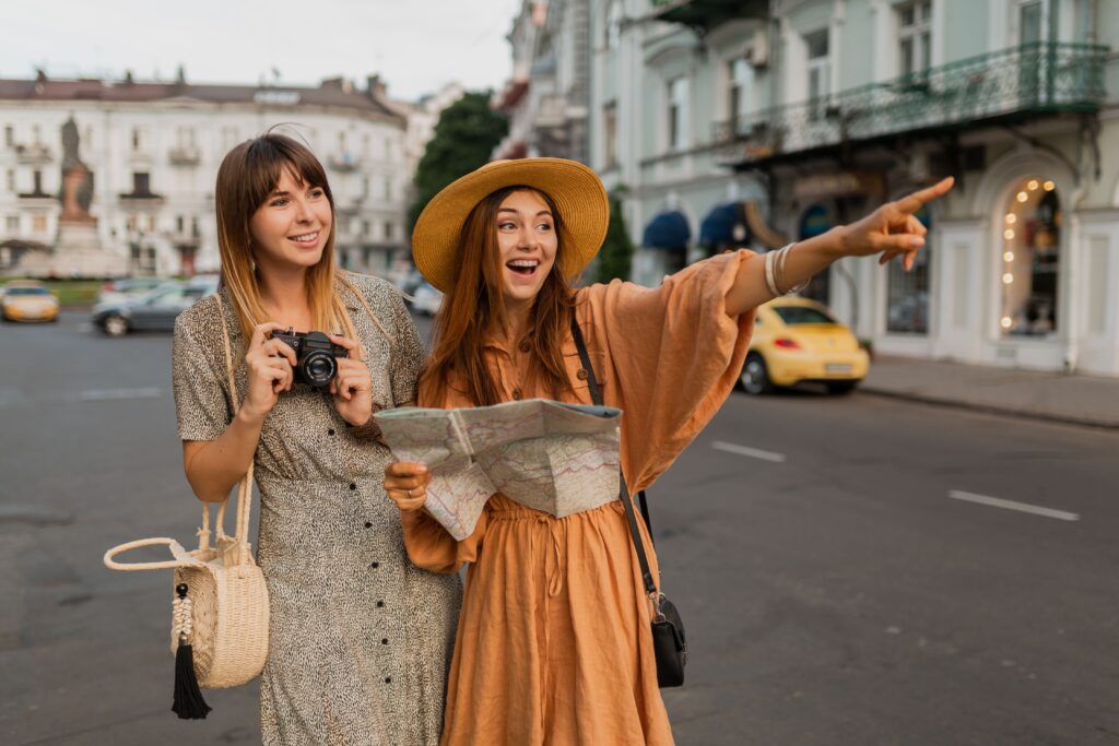 Stylish young women traveling together in Europe, wearing spring trendy dresses and accessories