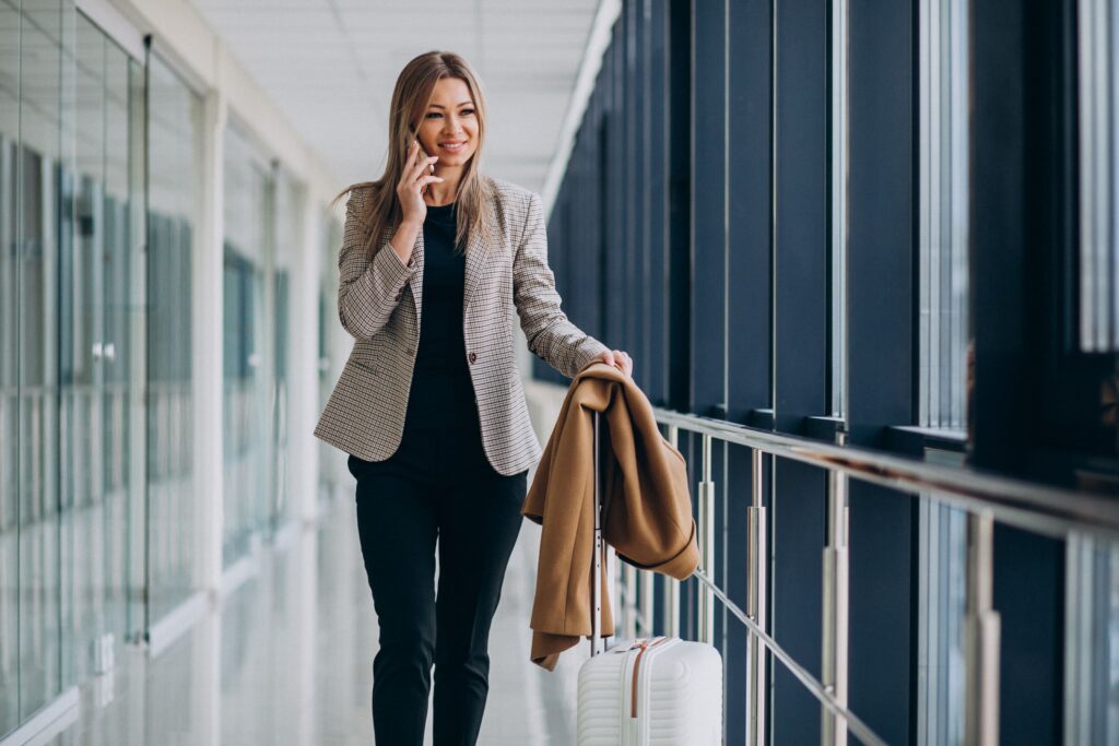 Business woman in terminal with travel bag talking on phone