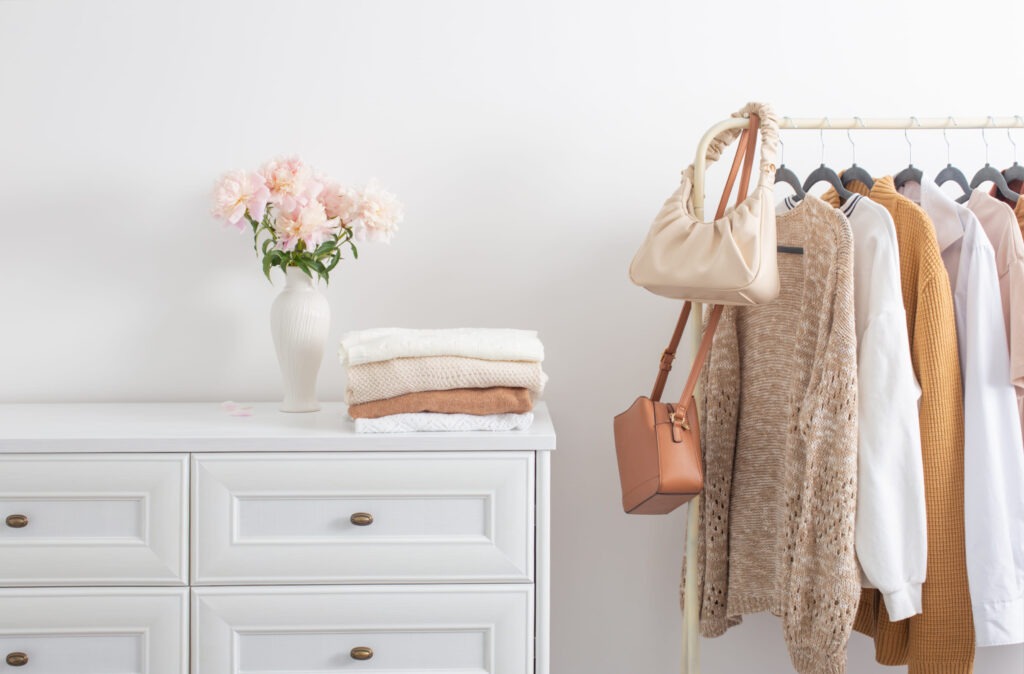 Capsule wardrobe full of neutral clothes on a hanger next to a wardrobe