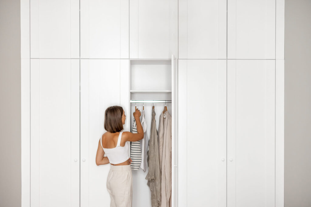 Woman sorting through her minimalist clothing collection in her wardrobe