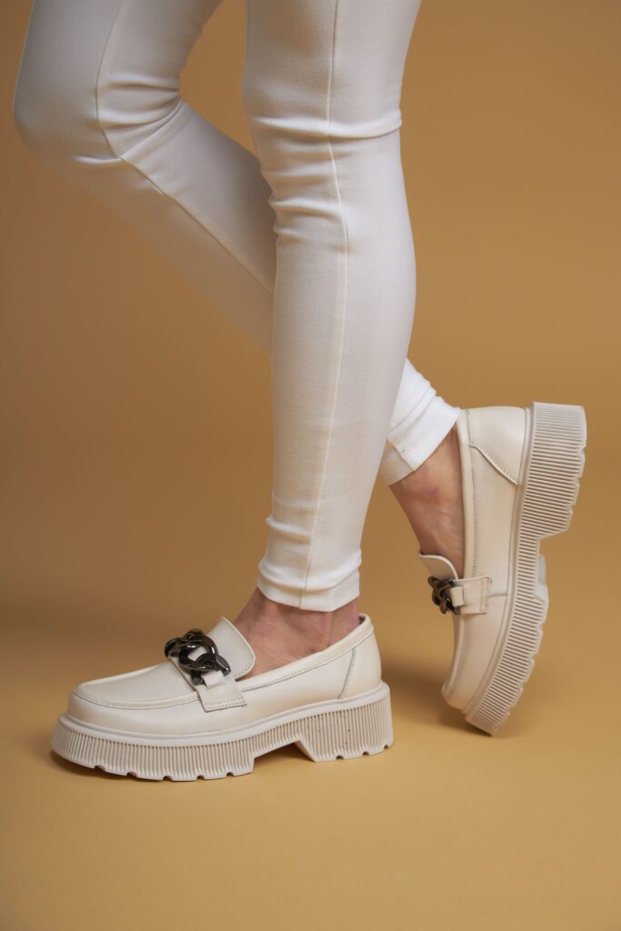 Image showcasing a pair of flawless female legs clad in white designer pants and summer shoes, set against a yellow background.