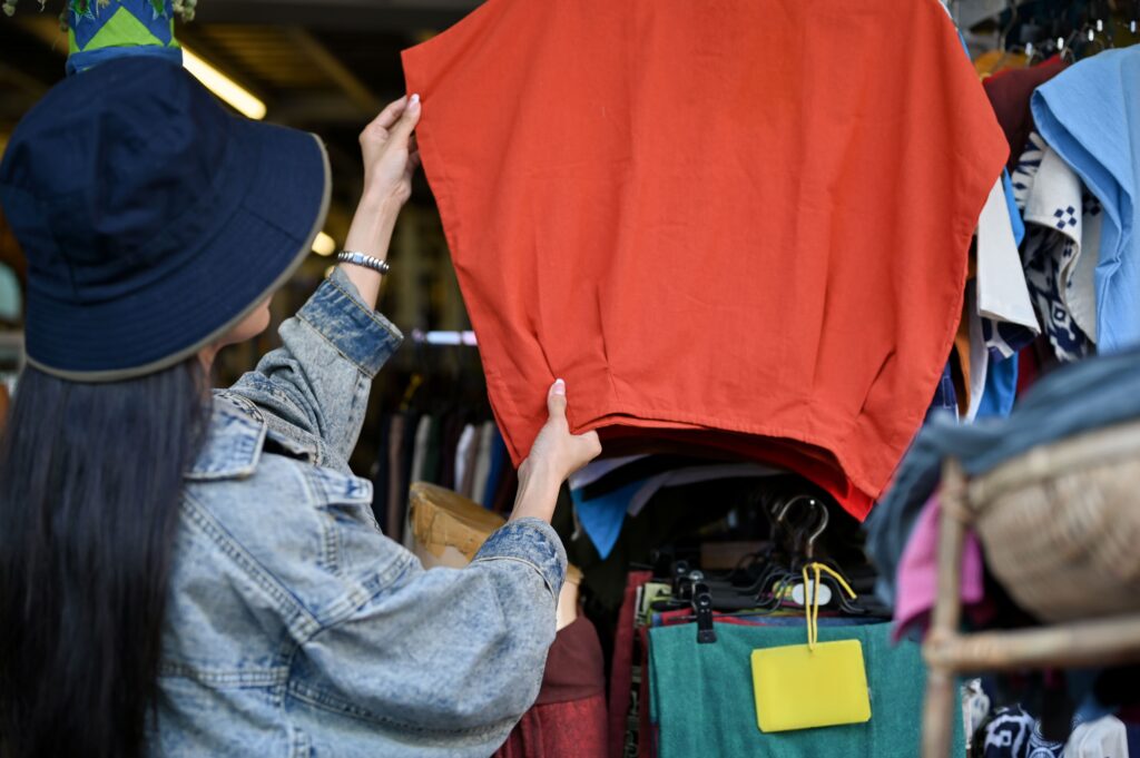 Image of a woman purchasing a budget-friendly local shirt at a store while on vacation or holiday.