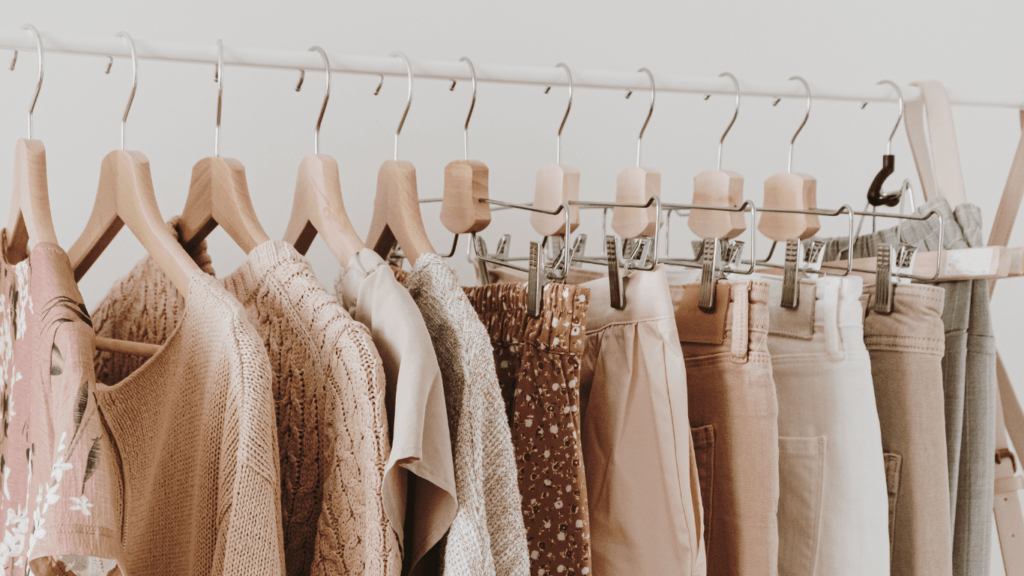 Chic women's blouses, sweaters, trousers, denim, and tees hanging on a rack against a white backdrop. Ideal for fashion blogs, websites, or social media cover images.