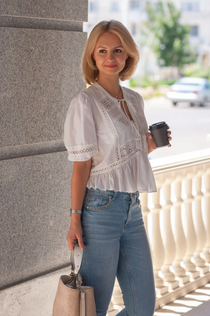 Image of an attractive girl in casual women's attire, holding a coffee while embodying an urban style.