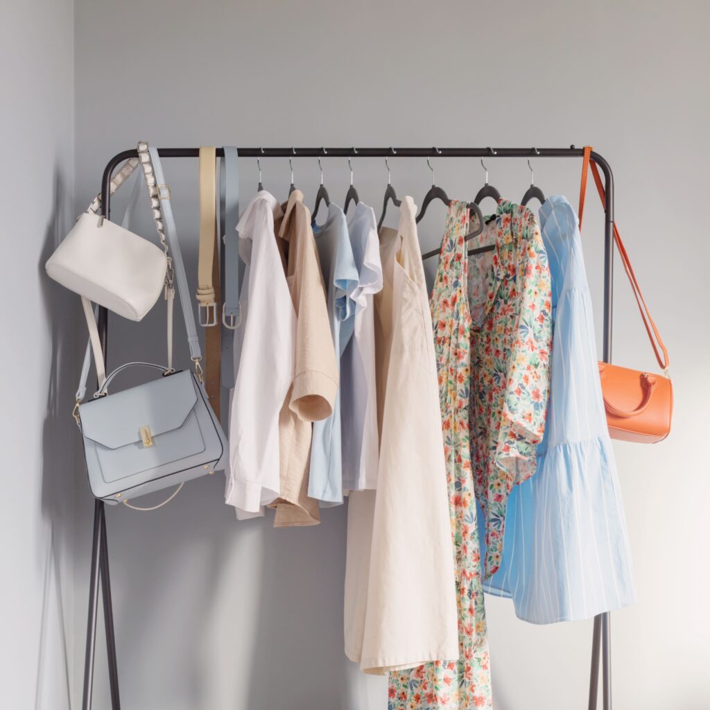Sustainable summer capsule wardrobe with light-colored women's clothes on hangers.
