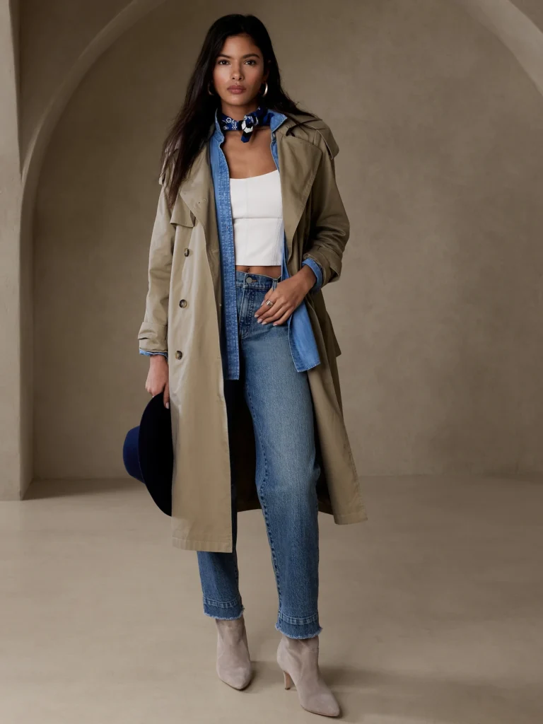 Image of a woman exemplifying versatility in a wardrobe, stylishly attired in a trench coat and jeans.