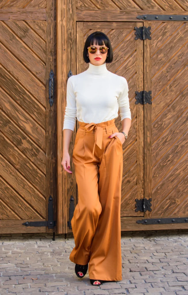 Fashionable outfit slim tall lady fashion and style concept woman walk in loose pants woman fashionable brunette stand outdoors wooden background girl with makeup posing in fashionable clothes