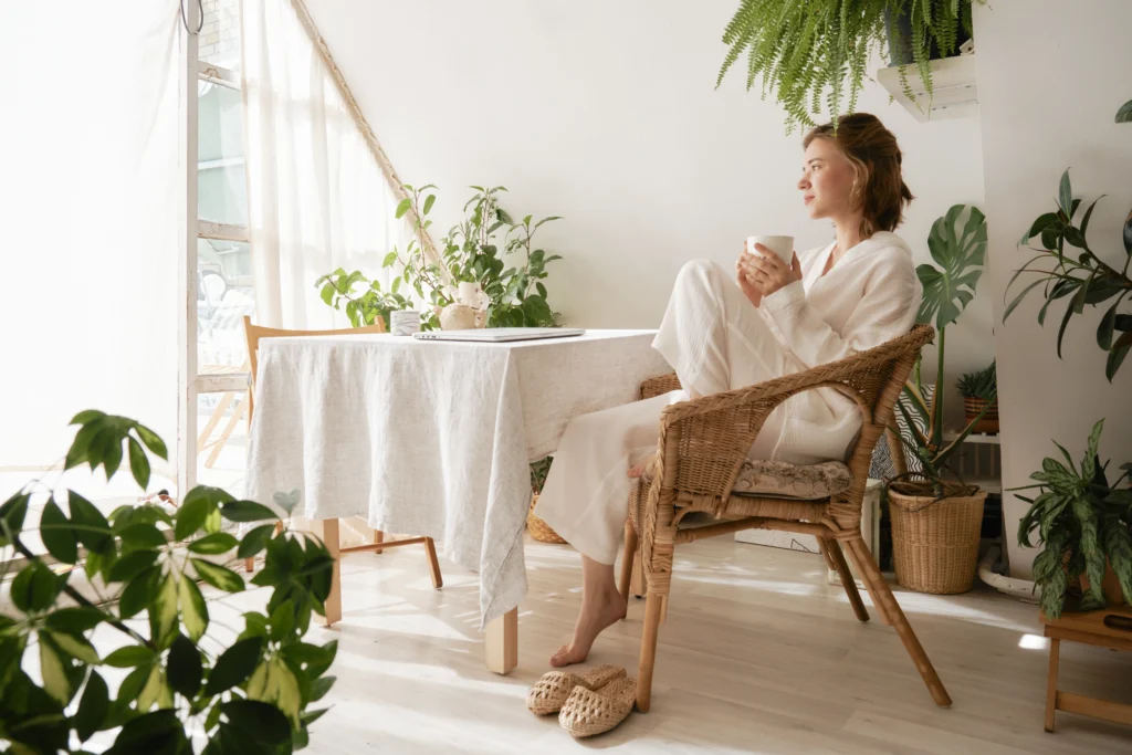 Young girl in a beautiful cozy white muslin pajamas sitting drinking coffee and thinks about her