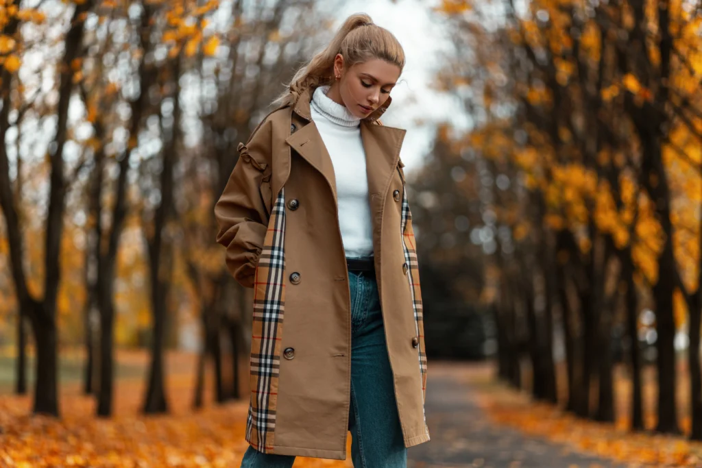 Woman in chic coat styled with accessories in a park setting.