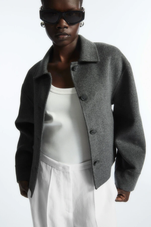 brands like cos model wearing a gray jacket and neutral tone shirt