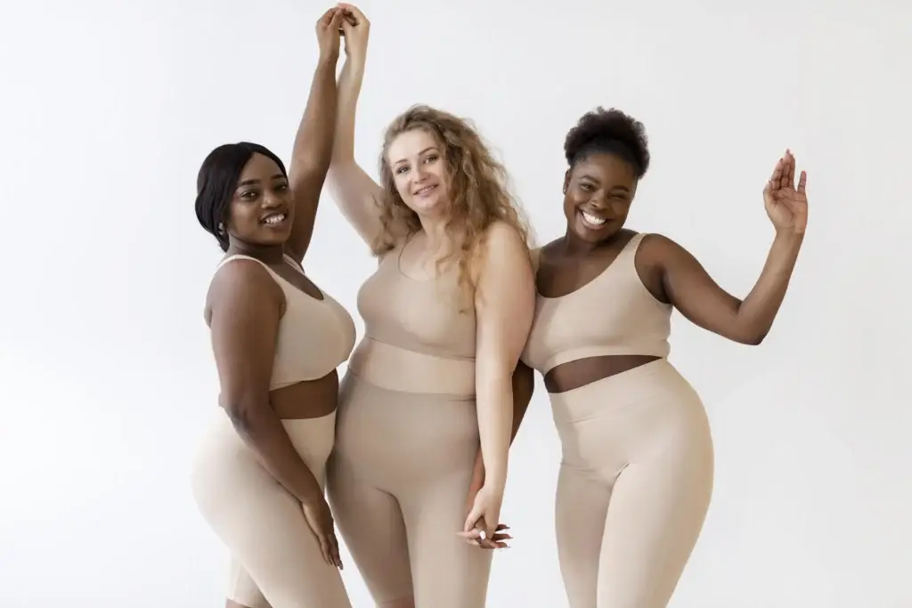 Three confident women posing together while wearing a body shaper