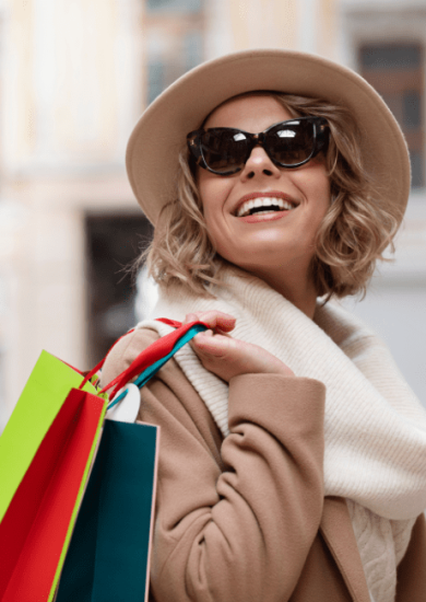 Medium shot of a cheerful woman carrying shopping bags, showcasing fashion on a budget