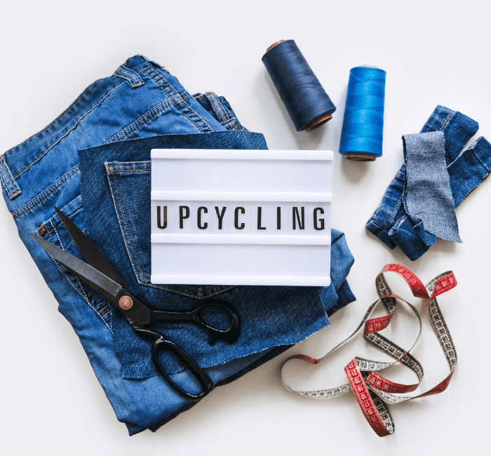 upcycle your old clothes with Denim Upcycling Ideas using Old Jeans: Repurposing and Reusing with Upcycle Clothes, Upcycle Fashion, and Upcycle Old Clothes. Lightbox with Text Upcycling, Stack of Old Blue Jeans, Scissors, Thread, and Sewing Tools in Sewing Studio.