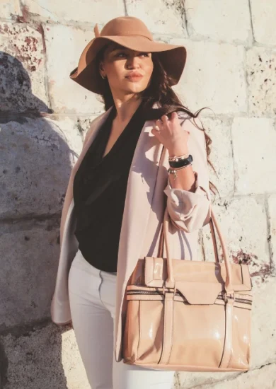 Plus-size model showcasing spring casual fashion with a neutral blazer, hat, and handbag, walking down the city street, displaying the art of accessorizing elegantly.