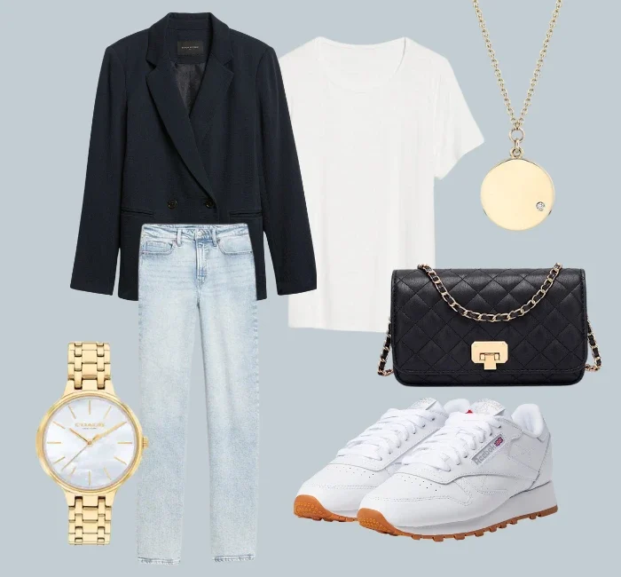 Fall capsule wardrobe 2023: An ensemble from the autumn capsule collection featuring a white shoe, a navy blue blazer, light wash denim jeans, a golden necklace and watch, completed with a black cross-body bag and crisp white shirt.