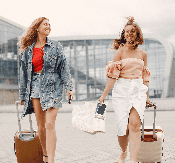 Two beautiful girls standing by the airport, showcasing their skill in traveling light
