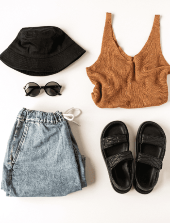 Capsule wardrobe for traveling: Women's stylish clothing and accessories flat lay on a white background, top view