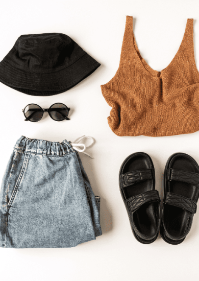 Capsule wardrobe for traveling: Women's stylish clothing and accessories flat lay on a white background, top view